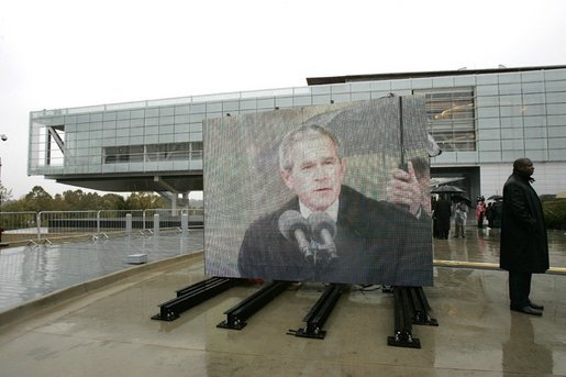 As pictured on an outdoor video screen, President George W. Bush addresses attendees during the dedication of former President Bill Clinton’s Presidential Center and Park in Little Rock, Ark., Nov. 18, 2004. "He was a tireless champion of peace in the Middle East. He used American power in the Balkans to confront aggression and halt ethnic cleansing. And in all his actions and decisions, the American people sensed a deep empathy for the poor and the powerless," said President Bush. White House photo by Eric Draper.