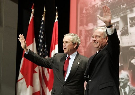 President George W. Bush and Prime Minister Paul Martin wave after their remarks at Pier 21, Canada's historic point of immigration in Halifax, Canada, Dec. 1, 2004. During his remarks, President Bush thanked Canada for the hospitality to more than 33,000 passengers whose airplanes were diverted because of the 911 attacks. "You opened your homes and your churches to strangers. You brought food, you set up clinics, you arranged for calls to their loved ones, and you asked for nothing in return," said the President.White House photo by Paul Morse
