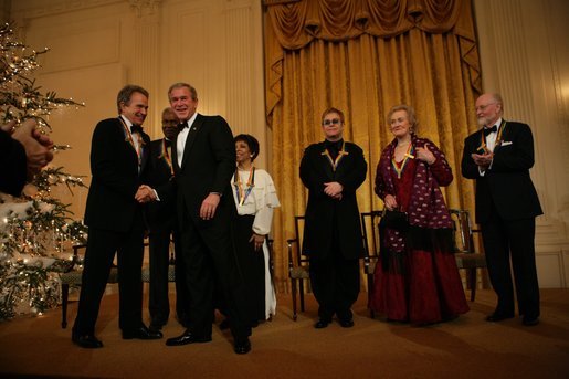 President George W. Bush greets Warren Beatty during a reception for the Kennedy Center Honors in the East Room of the White House, Sunday, Dec. 5, 2004. Also pictured, from left, are honorees Ossie Davis, Ruby Dee, Elton John, Joan Sutherland, and John Williams. White House photo by Eric Draper