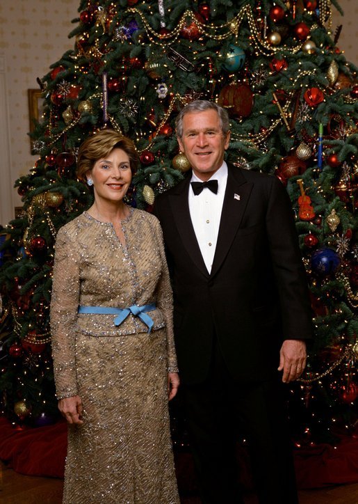 President George W. Bush and Laura Bush stand in front of the official White House Christmas Tree during the 2004 holiday season in the Blue Room of the White House. The White House celebrates the holidays with, "A Season Of Merriment and Melody," and include items like 350 instrument ornaments that adorn the Blue Room tree. White House photo by Eric Draper