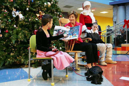Mrs. Bush reads "Dream Snow" by Eric Carle with help from her patient escorts, Brandy Robinson, left, and Keith "Koddie" Hernandez during the annual Children's National Medical Center holiday program in Washington, D.C., Wednesday, Dec. 15, 2004. White House photo by Susan Sterner
