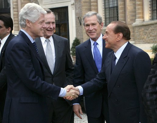 President George W. Bush and his father, former President George Bush, look on as Italian Prime Minister Silvio Berlusconi and former President Bill Clinton shake hands Thursday, April 7, 2005, prior to dinner at the Prime Minister's Rome residence. The visit came on the eve of Friday's funeral for Pope John Paul II. White House photo by Eric Draper