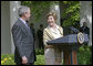 Laura Bush looks over to President Bush during a Rose Garden announcement honoring the 2005 Preserve America Presidential Awards Winners Monday, May 2, 2005. "These awards recognize collaborative efforts to protect and enhance our nation's cultural and historical heritage," said Mrs. Bush in her remarks. White House photo by Eric Draper