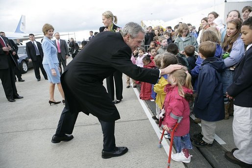 Greeted by flowers and smiles, President George W. Bush returns the gesture during his and Laura Bush's arrival in Maastricht, Netherlands, May 7, 2005. White House photo by Eric Draper