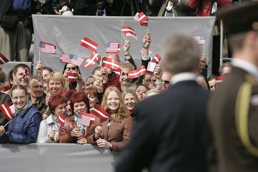 President George W. Bush turns to a crowd waving American and Latvian flags while visiting the Freedom Monument in Riga, May 7, 2005. White House photo by Paul Morse
