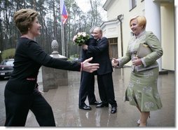 President George W. Bush and Russia President Vladimir Putin embrace in the background as Mrs. Bush reaches out to Lyudmila Putina, Russia's first lady, as the Bushes arrived Sunday, May 8, 2005, at the Putin residence shortly after their arrival in Moscow.  White House photo by Eric Draper