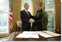 President George W. Bush and President Hamid Karzai of Afghanistan, shake hands Monday, May 23, 2005, in the Oval Office of the White House after signing a joint declaration that commits both the United States and Afghanistan to closely work together to enhance Afghanistan's long-term democracy, prosperity and security.  White House photo by Eric Draper