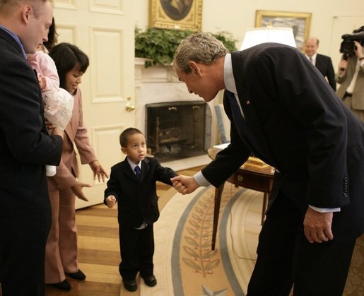 President George W. Bush reaches out for the hand of young Chandra Fincke, son of Lt. Colonel Mike Fincke and wife Renita, as the family joined fellow crewmembers of International Space Station flights for a visit to the Oval Office. White House photo by Eric Draper