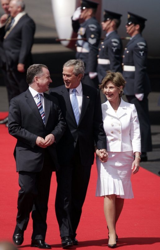 President George W. Bush and Laura Bush walk with Scotland's First Minister Jack McConnell during the playing of national anthems upon their arrival at Glasgow's Prestiwick Airport, July 6, 2005. White House photo by Paul Morse
