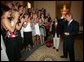 President Bush is applauded by members of the University of Georgia women's swimming and diving team, as he prepares put on the team hat Tuesday, July 12, 2005 at The White House, as part of ceremonies honoring the 2004 and 2005 NCAA Sport Championship teams. White House photo by Eric Draper