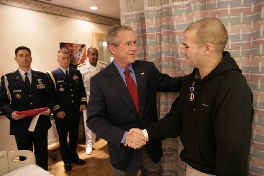 President George W. Bush shakes the hand of Cpl. Sean Locker after presenting the Marine with the Purple Heart Saturday, July 30, 2005, at the National Naval Medical Center in Bethesda, Md. Cpl. Locker, from Jessup, Md., is recovering from injuries suffered while serving in Operation Iraqi Freedom. White House photo by Eric Draper