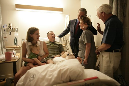 President George W. Bush hugs Molly Sloan, mother of Capt. Stephen "Kyle" Sloan, during a visit with the Marine and his family Saturday, July 30, 2005, at the National Naval Medical Center in Bethesda, Md. Other members of the family include Capt. Sloan's wife, Courtney, 10-month-old son Samuel, and father, Carlos. Capt. Sloan is recuperating from injuries suffered during Operation Iraqi Freedom. White House photo by Eric Draper