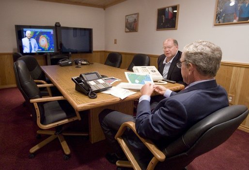 President George W. Bush is handed a map by Deputy Chief of Staff Joe Hagin, center, during a video teleconference with federal and state emergency management organizations on Hurricane Katrina from his Crawford, Texas ranch on Sunday August 28, 2005. White House photo by Paul Morse