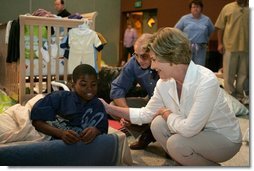 Laura Bush visits with a young boy displaced by Hurricane Katrina in the Cajundome at the University of Louisiana in Lafayette, La., Friday, Sept. 2, 2005.  White House photo by Krisanne Johnson