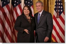 President George W. Bush stands with Volunteer Service Award recipient Marie Arcos of Houston, Texas, in the East Room of the White House, Friday, Oct. 7, 2005, where President Bush honored six recipients of the President's Volunteer Service Awards, as part of the celebration of Hispanic Heritage Month.  White House photo by Eric Draper