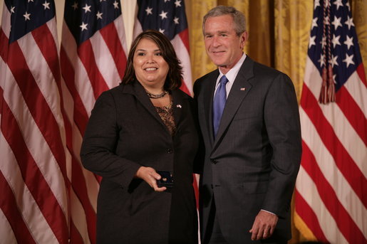 President George W. Bush stands with Volunteer Service Award recipient Marie Arcos of Houston, Texas, in the East Room of the White House, Friday, Oct. 7, 2005, where President Bush honored six recipients of the President's Volunteer Service Awards, as part of the celebration of Hispanic Heritage Month. White House photo by Eric Draper