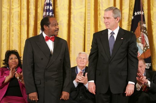 President George W. Bush exchanges a glance with Paul Rusesabagina during the presentation of the Presidential Medal of Freedom in the East Room Wednesday, Nov. 9, 2005. Paul Rusesabagina demonstrated remarkable courage and compassion in the face of genocidal terror. During the Rwandan genocide in 1994, he risked his own life to shelter more than 1,000 fellow Rwandans targeted for murder. White House photo by Paul Morse