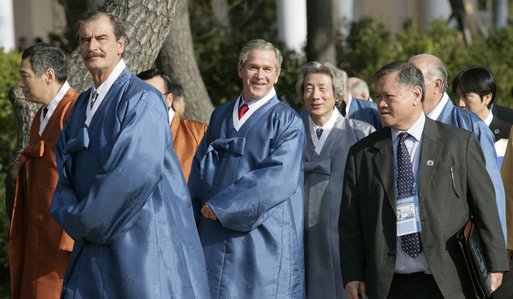 President George W. Bush peaks out behind Mexico President Vincente Fox, left, with Japan's Prime Minister Junichiro Koizumi as APEC leaders walk to the official photograph site Saturday, Nov. 19, 2005, at the Nurimaru APEC House in Busan, Korea. White House photo by Eric Draper