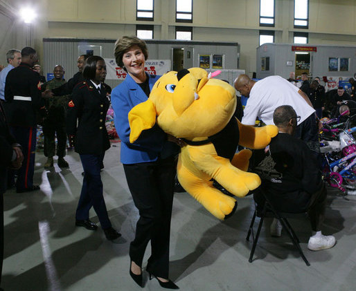 Mrs. Laura Bush helps carry a large stuffed animal to a toy distribution vehicle, Monday, Dec. 19, 2005, at the "Toys for Tots" collection center at the Naval District Washington Anacostia Annex in Washington, D.C., where she joined President George W. Bush in thanking the U.S. Marines for their charitable efforts. White House photo by Shealah Craighead