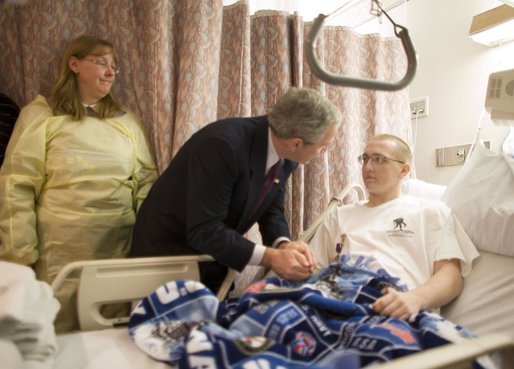 President George W. Bush grasps the hand of U.S. Navy Hospitalman Apprentice Tony Bullene of Watertown, S.D., after presenting him with a Purple Heart, with his mother, Carol Bullene, looking on Wednesday, Dec. 21, 2005, at the National Naval Medical Center in Bethesda, Md. White House photo by Paul Morse