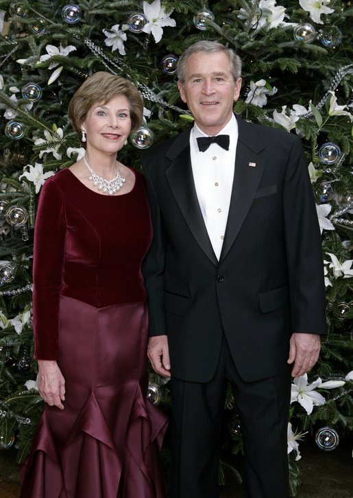 President George W. Bush and Laura Bush stand before the White House Christmas tree in the Blue Room of the White House. In keeping with this year's theme, "All Things Bright and Beautiful!" the Fraser fir is decorated with fresh white lilies. White House photo by Eric Draper
