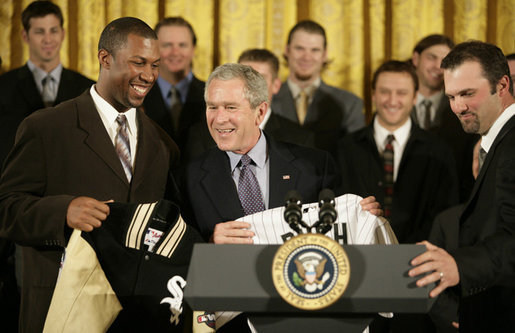 President George W. Bush is presented with a Chicago White Sox jacket and baseball jersey, Monday, Feb. 13, 2006 by White Sox players Jermaine Dye, left, and Paul Konerko in the East Room of the White House, where President Bush honored the 2005 World Series Champions. White House photo by Eric Draper