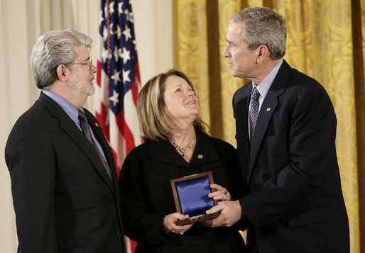 President George W. Bush presents a National Medal of Technology, Monday, Feb. 13, 2006 to George Lucas, left, and Chrissie England, of Industrial Light and Magic of San Francisco, Calif., during ceremonies in the East Room of the White House. White House photo by Eric Draper