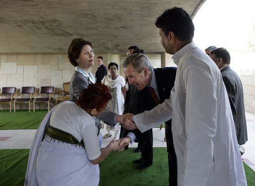President George W. Bush reaches to shake the hand of Dr. Nirmila Deshpande, as Laura Bush exchanges handshakes with Rajnish Kumar after they were met by the pair Thursday, March 2, 2006 in Rajghat, India for the wreath-laying ceremony at the Mahatma Gandhi Memorial. White House photo by Eric Draper
