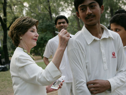 Mrs. Laura Bush signs the jerseys of students from the Schola Nova school and the Islamabad College for Boys, Saturday, March 4, 2006, who participated in a cricket clinic with President George W. Bush at the Raphel Memorial Gardens on the grounds of the U.S. Embassy in Islamabad, Pakistan. White House photo by Shealah Craighead