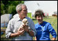 President George W. Bush holds the offspring of a stray dog during a tour of the animal rescue area of the Hands On Network base camp in Biloxi, Mississippi, Thursday, April 27, 2006. Pictured with the President is Disaster Response Coordinator Erika Putinsky. White House photo by Eric Draper