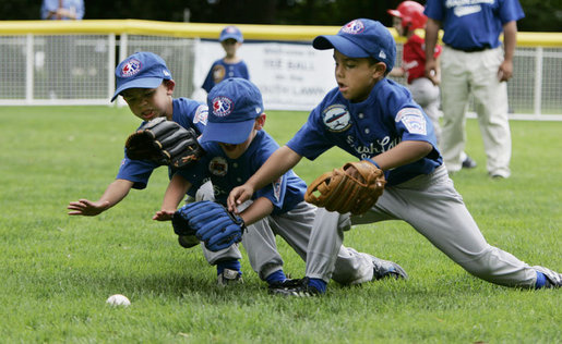 Three players for the Dolcom Little League Indians of the Naval Submarine Base in Groton, Ct., all dive for the ball on the South Lawn of the White House during action in the opening game of the 2006 Tee Ball season, Friday, June 23, 2006, between the McGuire Air Force Base Little League Yankees and the Dolcom Little League Indians. White House photo by Paul Morse