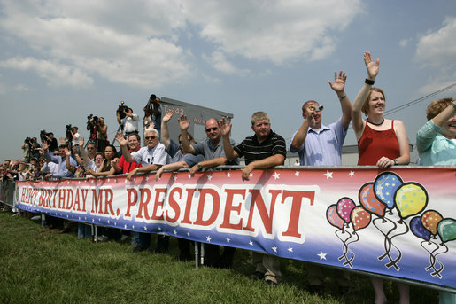 Standing behind a banner wishing President George W. Bush a happy birthday a crowd waves to President Bush, who celebrated his 60th birthday Thursday, as he departs from Chicago, Friday, July 7, 2006. White House photo by Eric Draper