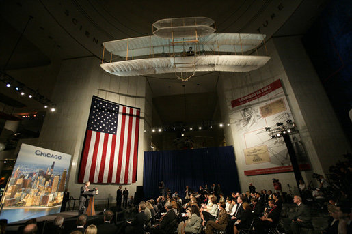 President George W. Bush speaks beneath a replica of the Wright Brother’s plane as he addresses a news conference at the Museum of Science and Industry in Chicago, Friday, July 7, 2006, speaking on the economy, immigration reform and security issues. White House photo by Eric Draper