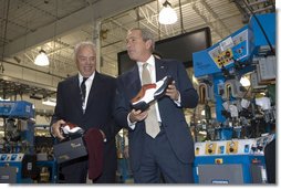 President George W. Bush holds up red, white and blue shoes presented to him by CEO John Stollenwerk during his visit to the Allen-Edmonds Shoe Corporation in Port Washington, Wis., Tuesday, July 11, 2006. White House photo by Kimberlee Hewitt