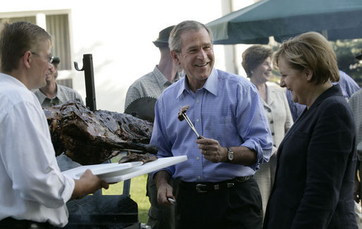 President George W. Bush enjoys a bit of barbeque Thursday, July 13, 2006, as he joins Chancellor Angela Merkel for a barbeque in Trinwillershagen. The President and Mrs. Laura Bush are scheduled to depart Germany Friday for St. Petersburg, Russia. White House photo by Eric Draper