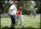 A player for the Thurmont Little League Civitan Club of Frederick Challengers of Thurmont, Md., is accompanied to first base by a South Lawn buddy Sunday, July 30, 2006, at the White House Tee Ball on the South Lawn game against the Shady Spring Little League Challenger Braves of Shady Spring W. Va. White House photo by Paul Morse