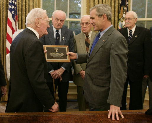 President George W. Bush is presented with a plaque at his meeting with members of the Supreme Headquarters Allied Expeditionary Force/Headquarters European Theater of Operations U.S. Army Veterans Association Friday, Oct. 6, 2006, in the Oval Office at White House. The group was organized in 1985 as a way to pay tribute to the memory of their supreme commander, Dwight D. Eisenhower, and their visit to the White House marks their 21st and final reunion gathering. White House photo by Paul Morse