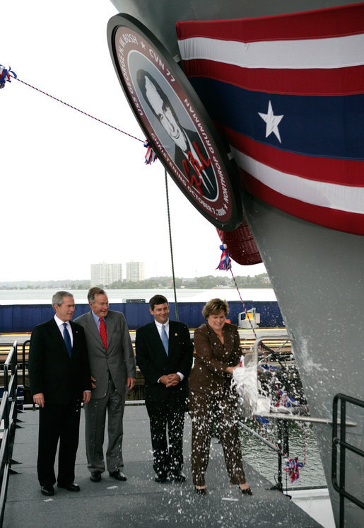 President George W. Bush joins his father, Former President George H. W. Bush and Northrop Grumman President Mike Petters, as his sister Doro Bush Koch breaks the bottle to christen the George H.W. Bush (CVN 77) in Newport News, Virginia, Saturday, Oct. 7, 2006. White House photo by Eric Draper