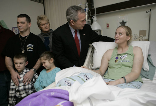 President George W. Bush congratulates Army Specialist Sue Downes after presenting the Iowa City, Iowa soldier with a Purple Heart Friday, Dec. 22, 2006, at the Walter Reed Army Medical Center where she is recovering from injuries suffered in Operation Iraqi Freedom. Joining in the presentation is Pvt. Downes' husband, Gabriel, their son Austin and daughter Alexis, and mother, Faye Partin. White House photo by Eric Draper