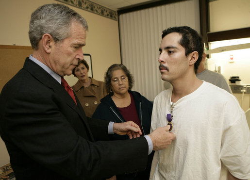 President George W. Bush presents the Purple Heart to U.S. Army Staff Sgt. Robert Cordero of El Paso, during a visit Friday, Dec. 22, 2006, to the Walter Reed Army Medical Center where the soldier is recovering from injuries suffered in Operation Iraqi Freedom. Looking on with Mrs. Laura Bush is Sgt. Cordero's mother, Rosa. White House photo by Eric Draper