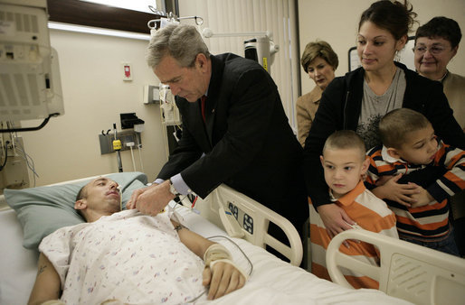 President George W. Bush presents a Purple Heart to Sgt. John Kriesel of Twin Cities, Minn., during a visit Friday, Dec. 22, 2006, to Walter Reed Army Medical Center where the National Guardsman is recovering from injuries suffered in Operation Iraqi Freedom. Looking on with Mrs. Laura Bush is Sgt. Kriesel's wife, Katie, holding their 4-year-old son Broden and 5-year-old son Elijah. White House photo by Eric Draper