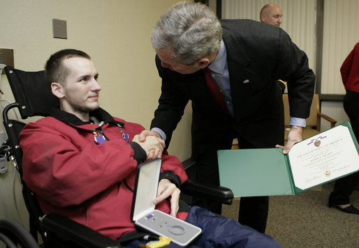 President George W. Bush congratulates Pvt. First Class Tony Brawdy of Tulsa, OK., after presenting him with two Purple Hearts Friday, Dec. 22, 2006, during a visit to Walter Reed Army Medical Center, where the soldier is recovering from injuries suffered in Operation Iraqi Freedom. White House photo by Eric Draper