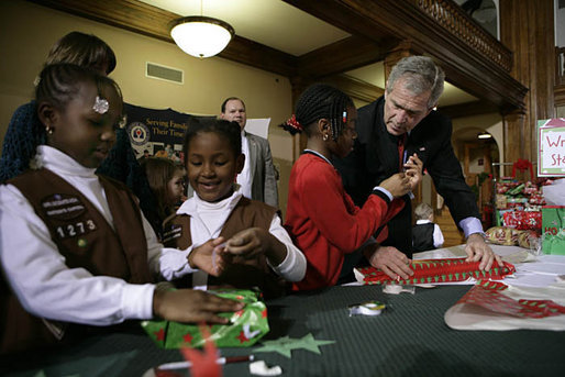 President George W. Bush helps young volunteers wrap presents for families of soldiers who were wounded in Iraq and Afghanistan, Friday, Dec. 22, 2006, at Walter Reed Army Medical Center in Washington, D.C. White House photo by Eric Draper