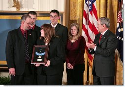 President George W. Bush presents the Medal of Honor to the family of Corporal Jason Dunham of the Marine Corps during a ceremony in the East Room Thursday, Jan. 11, 2007. The President spoke of Cpl. Dunham, "In April 2004, during an attack near Iraq's Syrian border, Corporal Dunham was assaulted by an insurgent who jumped out of a vehicle that was about to be searched. As Corporal Dunham wrestled the man to the ground, the insurgent rolled out a grenade he had been hiding. Corporal Dunham did not hesitate. He jumped on the grenade, using his helmet and body to absorb the blast. Although he survived the initial explosion, he did not survive his wounds. But by his selflessness, Corporal Dunham saved the lives of two of his men, and showed the world what it means to be a Marine."  White House photo by Paul Morse