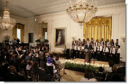 President George W. Bush, standing with members of the Jackson High School Black History Tour Group of Jackson, Mich., welcomes guests to the East Room of the White House, Monday, Feb. 12, 2007, during the celebration of African American History Month. White House photo by Eric Draper