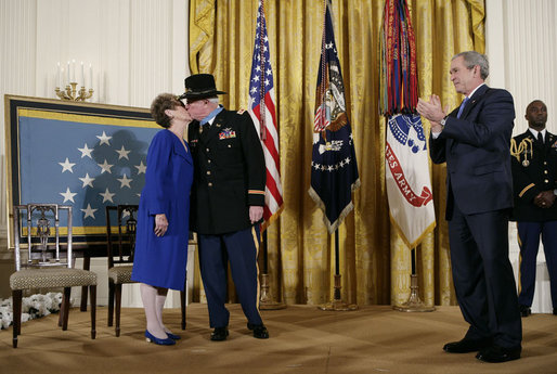 President George W, Bush applauds as Medal of Honor recipient U.S. Army Major Bruce P. Crandall kisses his wife, Arlene, in the East Room of the White House, Monday, Feb. 26, 2007. Crandall was awarded the Medal of Honor for his extraordinary heroism as a 1st Cavalry helicopter flight commander in the Republic of Vietnam in November 1965. White House photo by Eric Draper