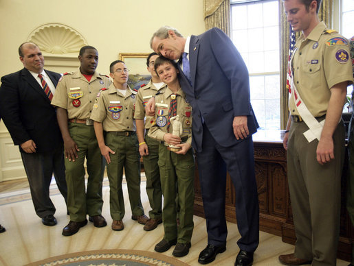President George W. Bush hugs Cub Scout Bryson Hicks, 10, of San Diego, Calif., as he is given a statue of a Cub Scout in the Oval Office Monday, Feb. 26, 2007. In 2005 Bryson rescued his 4-year-old cousin, who waded into a lake after a remote control boat. Byrson used skills he learned in Scouting to save save his cousin. The scouts presented the President with the Boy Scouts of America's Report to the Nation, highlighting the organization's accomplishments during the past year. White House photo by Eric Draper