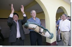 President George W. Bush holds a gift from Mayor Raymundo Juarez during a visit Monday, March 12, 2007, to Santa Cruz Balanya, Guatemala. Pictured at right is Guatemalan President Oscar Berger.  White House photo by Eric Draper