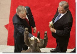 President George W. Bush lays a white rose in the palm of the Peace Statue as Guatemalan President Oscar Berger looks on Monday, March 12, 2007, at the Palacio Nacional de la Cultura in Guatemala City.  White House photo by Paul Morse