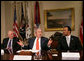President George W. Bush gestures as he talks with reporters following a meeting on financial literacy Wednesday, April 25, 2007 in the Roosevelt Room at the White House, where President Bush said he has directed U.S. Secretary of the Treasury Henry Paulson, left, to develop and hone a strategy that will help more of our American citizens to become financially literate.John Bryant, president and CEO of Operation Hope, is seen at right. White House photo by Eric Draper